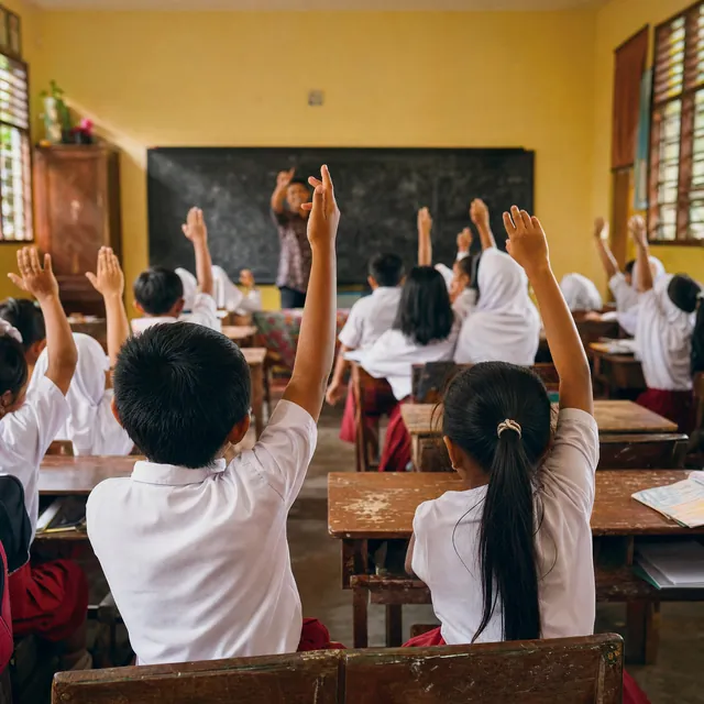 Schoolchildren seen from behind raise their hands toward the chalkboard