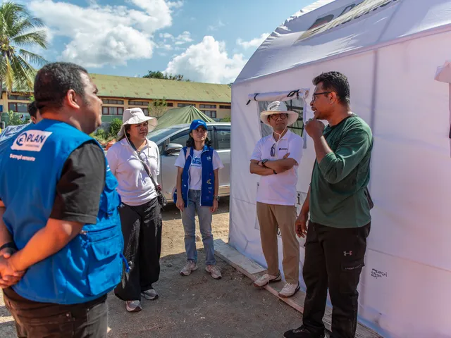 Partner institution representatives confer outside a temporary service tent at a programme site
